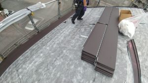 屋根の上で屋根のカバー工法施工中